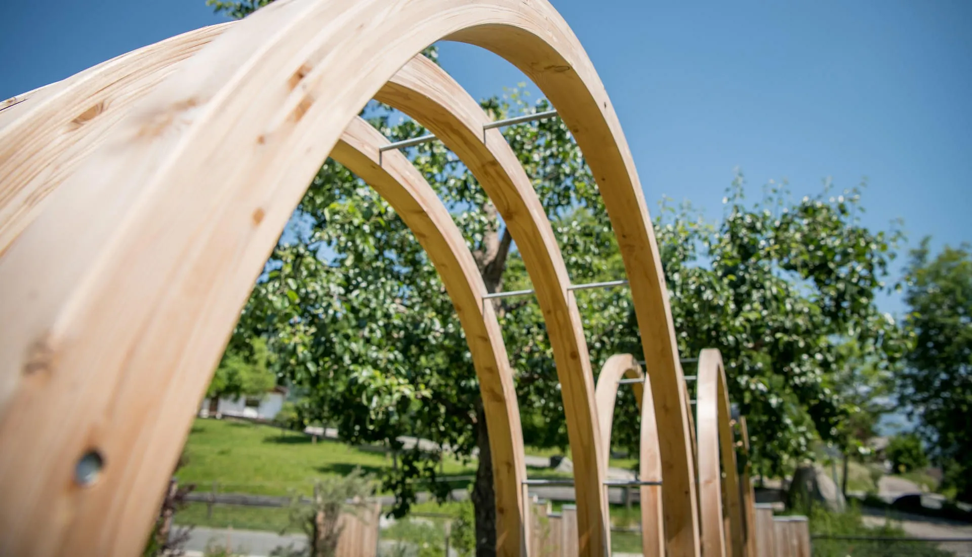 Ein aus Holz gefertigter Bogen in einem Garten an einem sonnigen Tag.&nbsp;