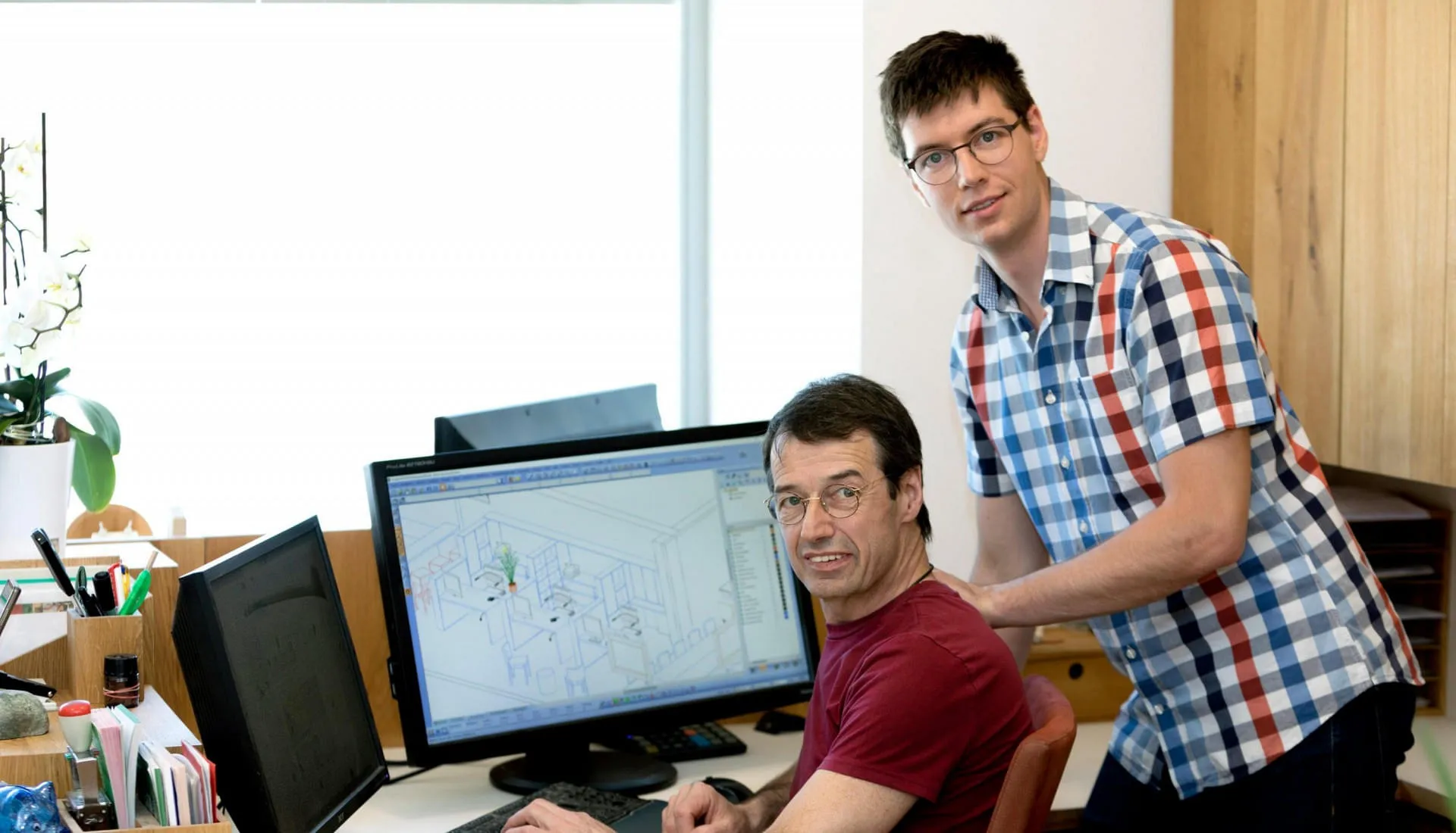 Tischlermeister Max Schlemaier und Sohn und Gesch&auml;ftsf&uuml;hrer Markus gemeinsam in einem B&uuml;ro w&auml;hrend sie an einem Computer arbeiten.&nbsp;